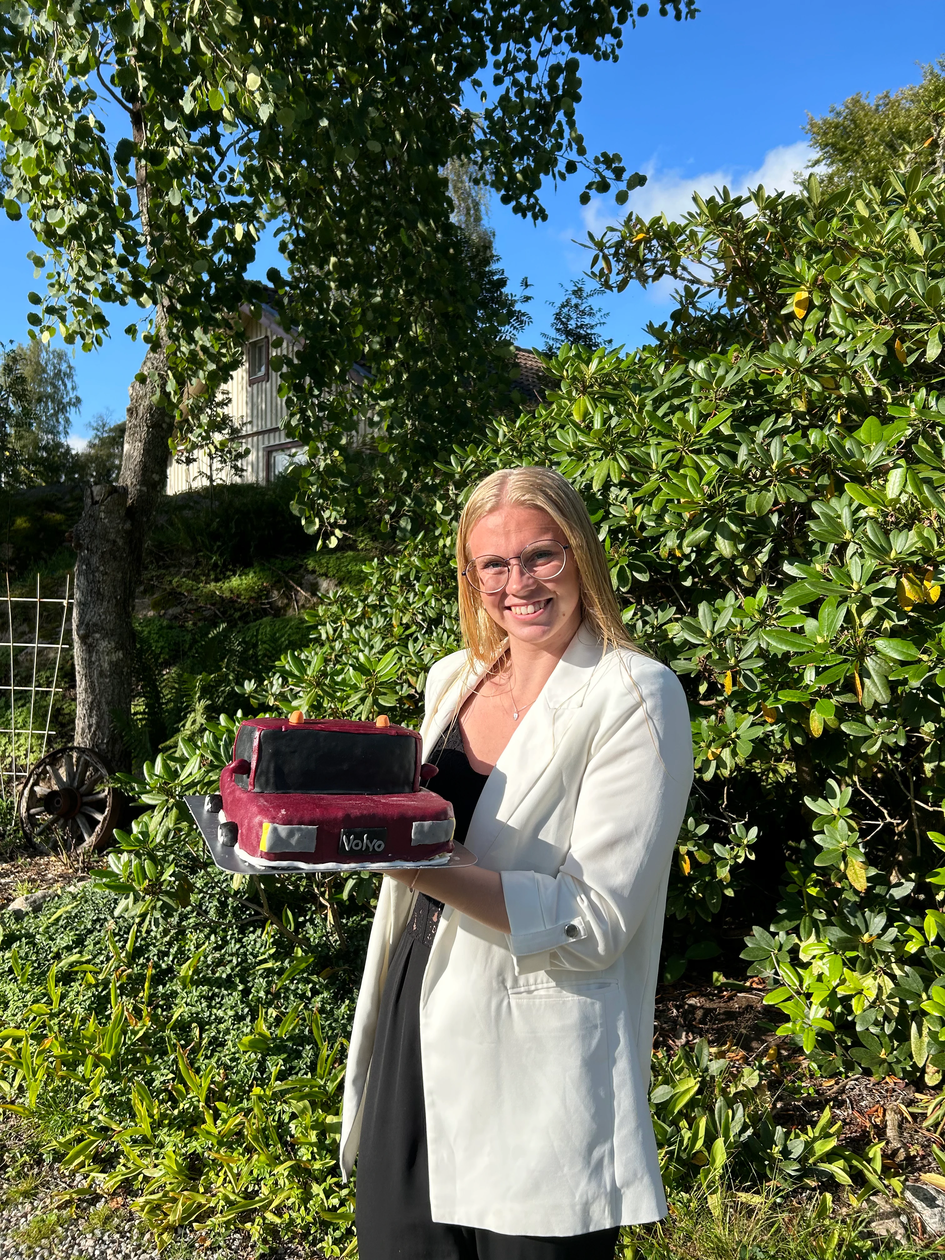 Josefine håller i en tårta formad som en Volvo omgjord till en a-traktor