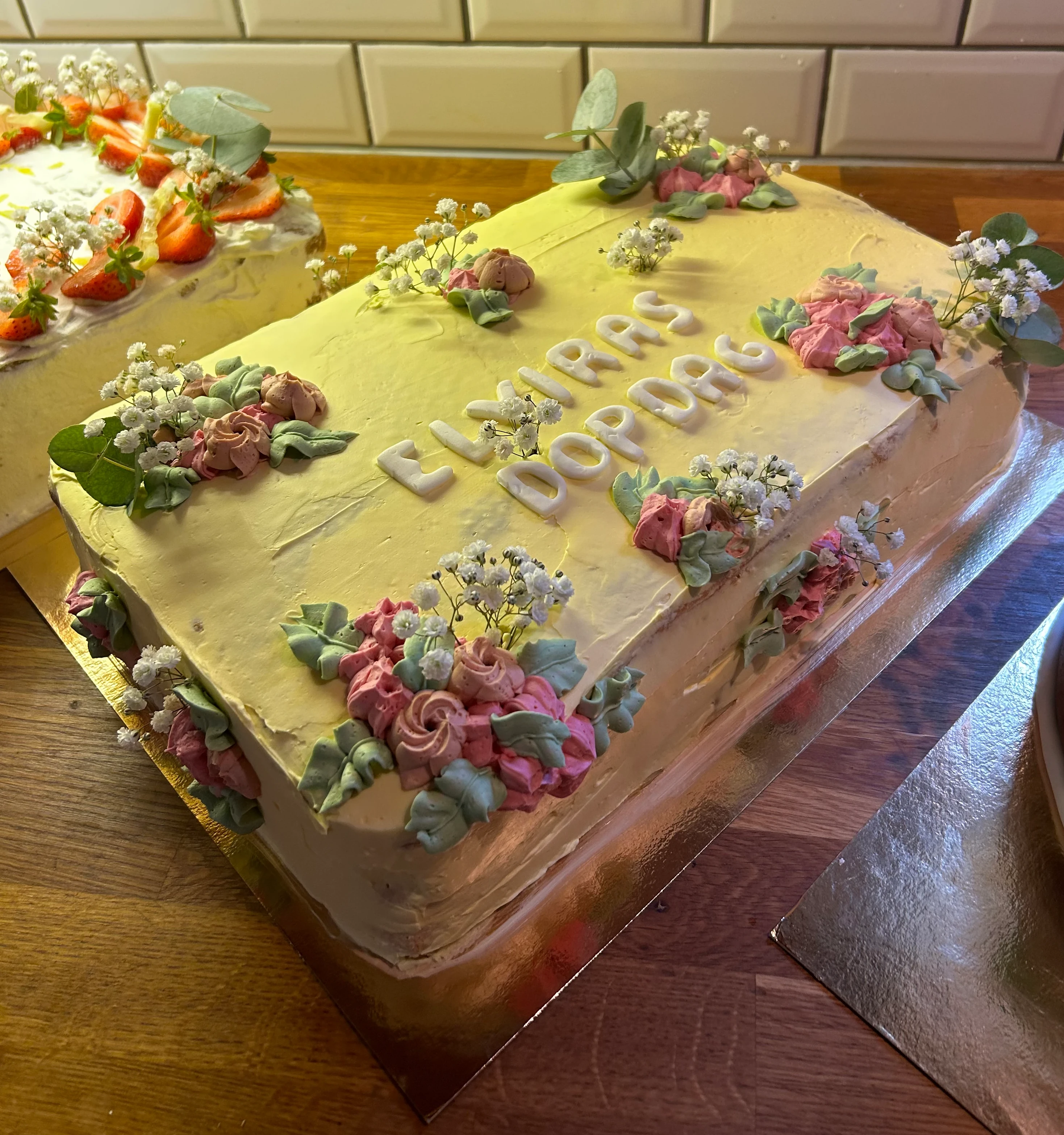Gul doptårta med många olika blomdekorationer